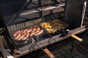 Grilling sausages and vegetables on outdoor barbecue grill