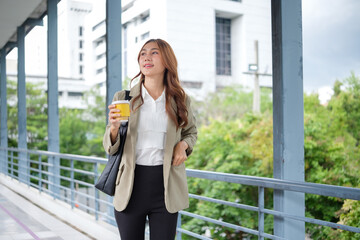 Happy businesswoman commuting to the office, enjoying her morning coffee and looking ready for a...