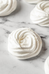 Meringues mini pavlova cakes close up on white marble background. Light summer dessert cooking