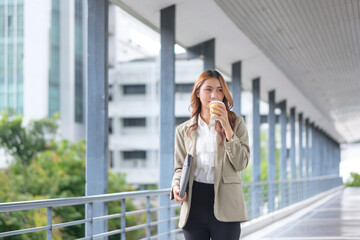 Happy businesswoman commuting to the office, enjoying her morning coffee and looking ready for a...