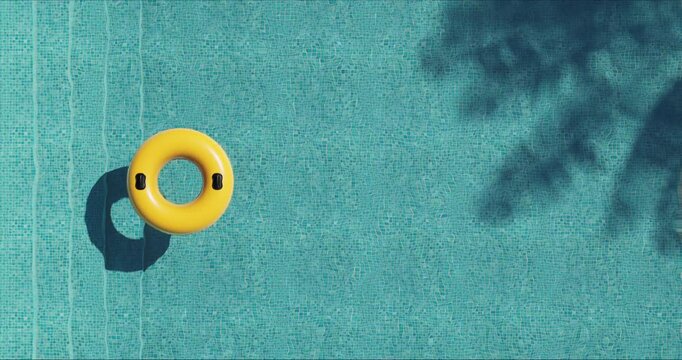 Top view of a vivid yellow inflatable ring floating on clear blue pool water. Sunlight and foliage cast shadows on the mosaic tiles. Calm, minimal scene evoking summer leisure and relaxation.
