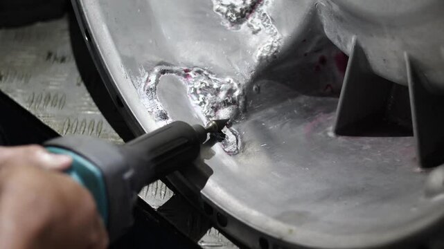 Close up hand repairing aluminium transmission case using bor cun or mini die grinder.
