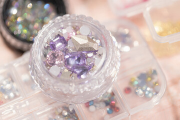 Nail art gems and rhinestones in small container bring beauty and fashion to home nail salon...