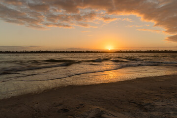 The sun setting over the Matanzas Inlet with clouds framing the picture and the sun reflecting in the water