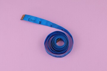 Blue measuring tape isolated on pink background. diet for weight loss concept.
