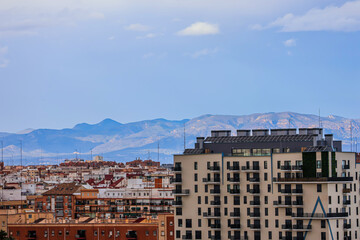 Diverse and colorful houses of a Spanish town with mountains on the horizon under a cloudy blue sky on a summer day	

