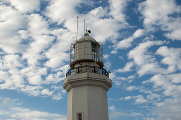 White Lighthouse Under Blue Sky with Scattered Clouds