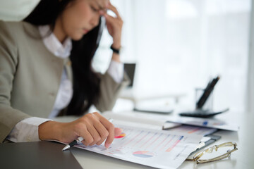 Close up of stressed businesswoman holding her head while analyzing financial reports.