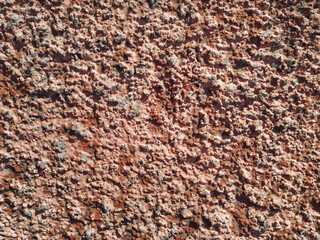 Rough wall surface covered with decorative plaster and putty. Painted pink. Background bumpy texture. Decorative materials.