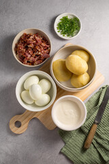 Cooking egg potato salad with bacon and fresh herbs in a plate