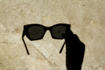 The shadow of sunglasses, cast on a textured wall, creates a unique and stylish image. A shadow of...