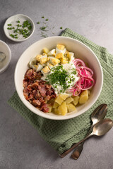 Egg potato salad with bacon and fresh herbs in a plate