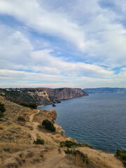 Coastal landscape with cliffs and ocean. The scene features a rocky shoreline, gentle waves, and a...