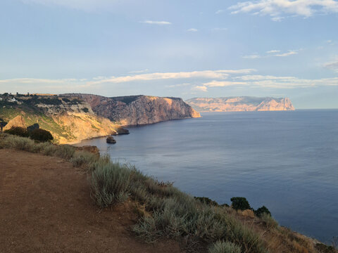 Coastal landscape with cliffs and ocean under a clear sky. The scene captures the beauty of nature and tranquility of the seaside.