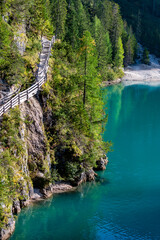 Scenic trail beside the stunning Lago di Braies in South Tyrol. Bright blue-green waters contrast...