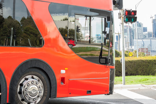 A large red bus waits at traffic lights