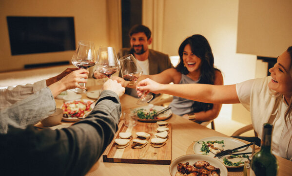 Friends enjoying a lively dinner with food and drinks around the table