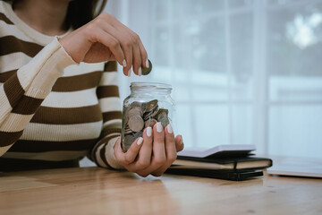A woman holds a piggy bank, which symbolizes savings, financial planning, and economic challenges....