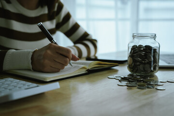 A woman holds a piggy bank, which symbolizes savings, financial planning, and economic challenges....