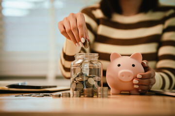 A woman holds a piggy bank, which symbolizes savings, financial planning, and economic challenges....