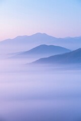 Obraz premium Serene mountain range enveloped in a soft, ethereal, and misty atmosphere.