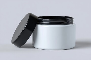 A white jar with a black lid sitting next to it on a light background