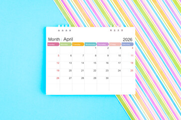 April 2026 desk calendar on blue and rainbow color background.