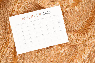 November 2026 calendar card on golden color textile background.