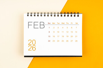 Desk calendar for February 2026 year on yellow color background, Flat lay.