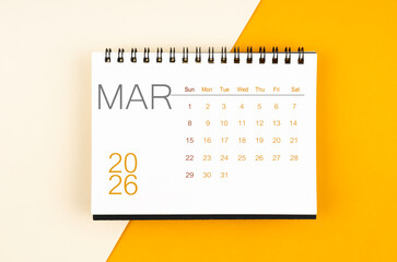 Desk calendar for March 2026 year on yellow color background, Flat lay.