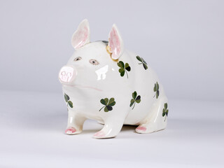 A Ceramic Pig Figurine with Four-Leaf Clover Decoration Isolated on White .

