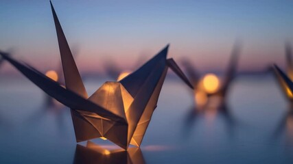 Close up paper cranes with light bulbs on nature background at sunset. August 6th. Origami crane as a symbol of peace. Peace Memorial Day.