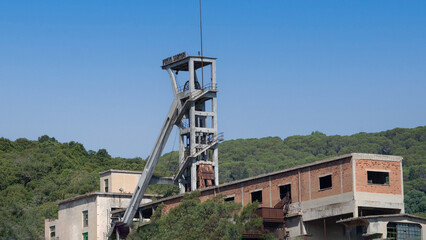 Rusty industrial tower stands isolated against a dry hillside covered with sparse vegetation