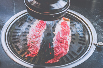 grilling meat on a charcoal grill in a korean restaurant