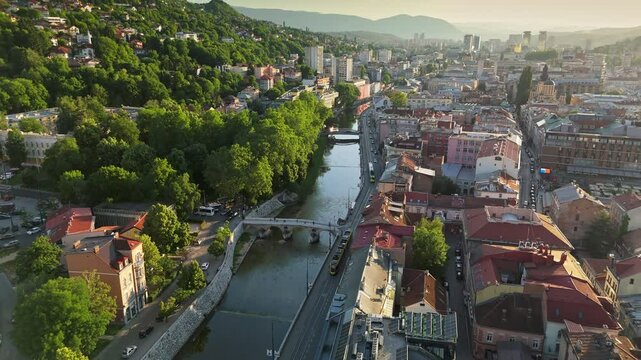 Scenic beauty of Sarajevo with aerial views of the Miljacka River and vibrant city life during sunset. Flying over summer Sarajevo, Bosnia and Herzegovina