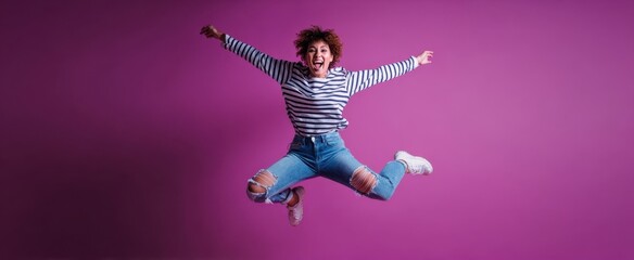 The joyful woman jumping in a vibrant pink studio backdrop.