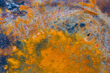 Detailed shot of rusted metal, showcasing textures and colorful patterns. Close-up abstract view of rusty metal surface with orange and dark patches, full of texture.