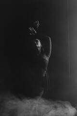 Obraz premium A mysterious woman stands in silhouette against a bright window, surrounded by dramatic smoke and shadows