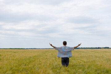 Embracing Nature: A Young Man Revels in the Vastness of a Golden Field Under an Expansive Sky,...