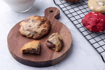 Assorted chocolate cookies on a board with milk and coffee