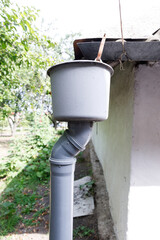 A Detailed View of a Gray Drainage System Residing by an Outdoor Space with Lush Greenery and Sunlight Filtering Through the Leaves, Highlighting Simple Yet Functional Design Elements
