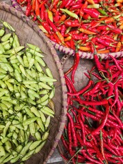 Freshly harvested green and red chili peppers in woven baskets.