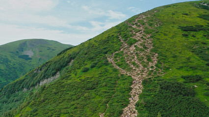 Aerial view of young tourists walking along a mountain trail to the top of the mountain.