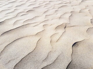 Nahaufnahme einer natürlich hellen Sanddüne auf Gran Canaria, Spanien, mit elegant gewellten Strukturen in weichem Licht