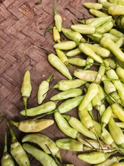 Fresh, pale green chili peppers on a woven surface.