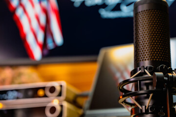 Modern home office desk setup with American Independence Day theme, including monitors displaying US flag wallpaper, bonsai tree, microphone, and warm cozy lighting ambiance.
