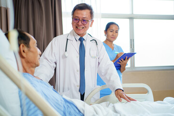 Doctor and nurse visit elderly male patient in recovery ward in hospital.