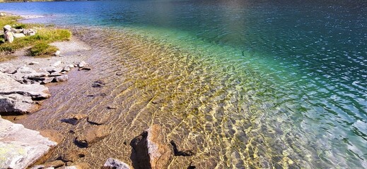 Julierpass Schweizer Alpen: kristallklares Wasser eines Bergsees in den Schweizer Bergen mit verschiedenen Blautönen, türkus und smaragdgrün mit sanften Wellen