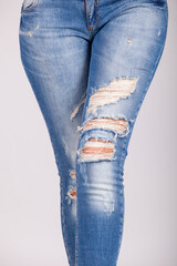 Woman's Legs in Trendy Ripped Blue Skinny Jeans. Distressed Denim Fashion