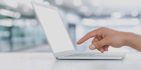 A hand pointing to a blank white laptop screen in a modern office environment representing technology, innovation, and digital workspace concepts for creative or professional use
